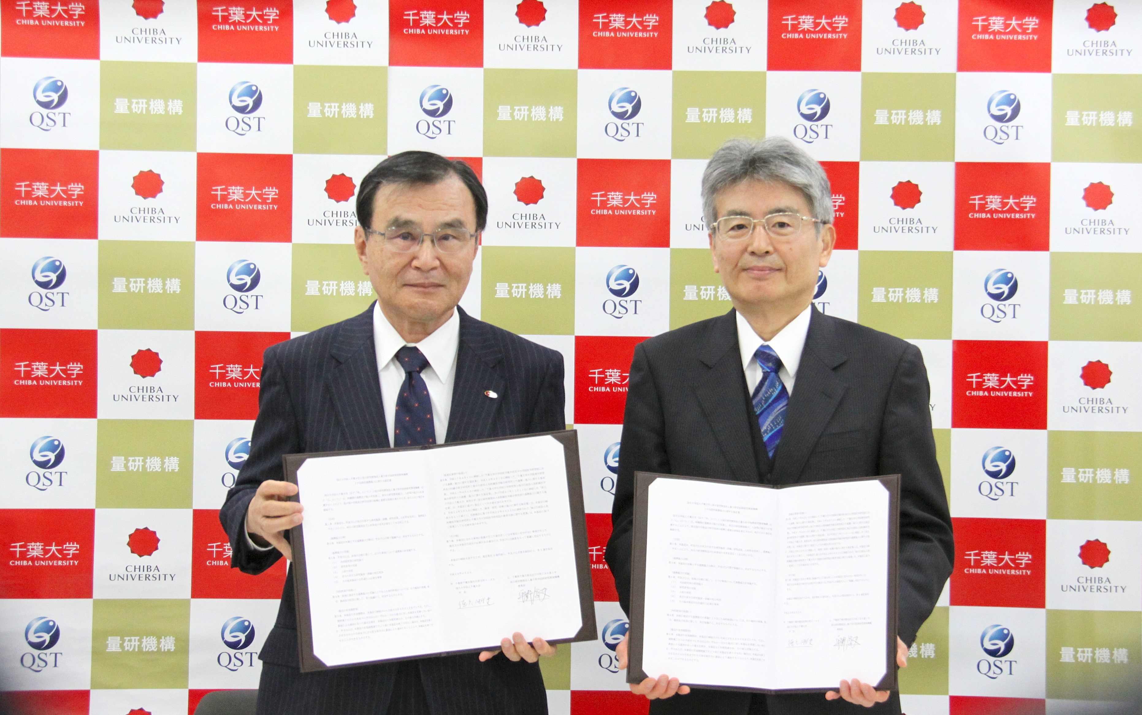 協定書を掲げる徳久学長と平野理事長