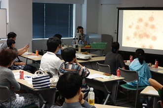 顕微鏡での実験の映像を交えながら紹介を行いました。（8日のサイエンスカフェ）の画像