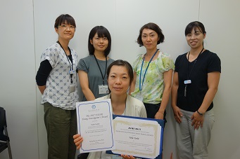 賞状を手にした吉井幸恵主幹研究員と研究チームメンバーの画像