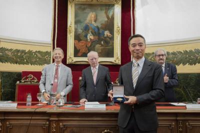 A man in a suit holding a commemorative medal.