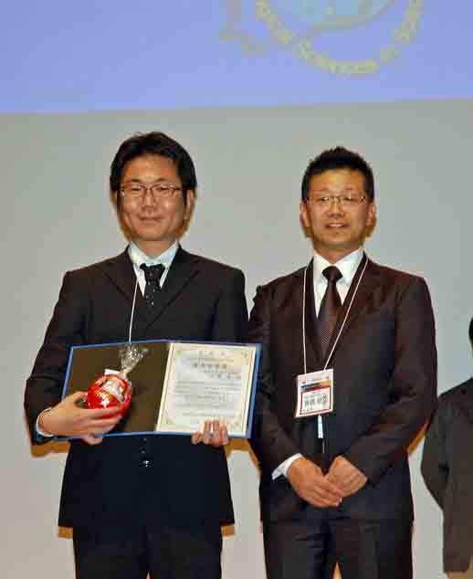 写真2：山崎晃実習生（向かって左）、高橋昭久大会長（右）の画像