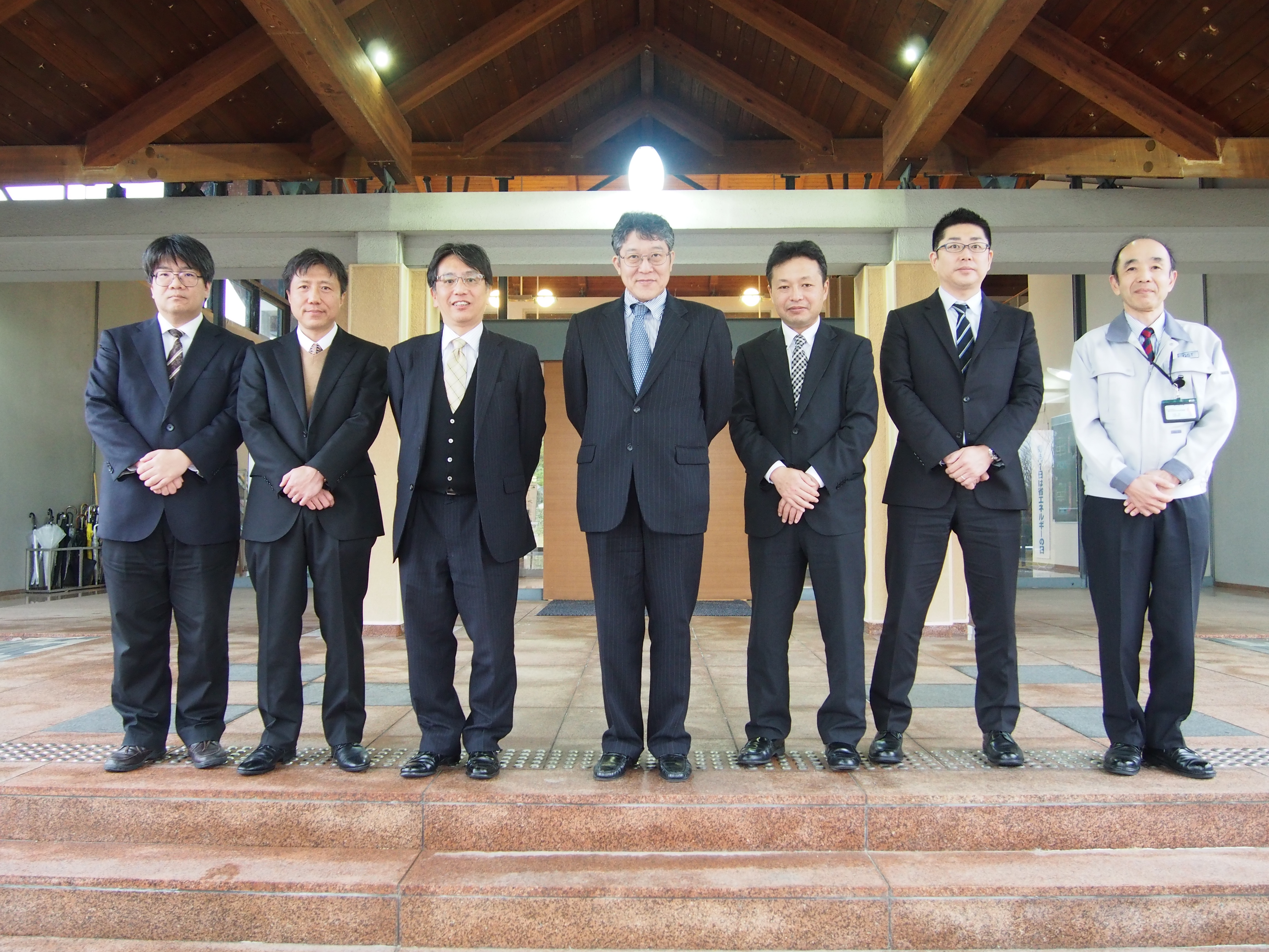 管理棟玄関において集合写真（右から、中谷副所長、津本様、三井課長、美並局長、内海所長、加道室代、長谷川研究主幹）の写真